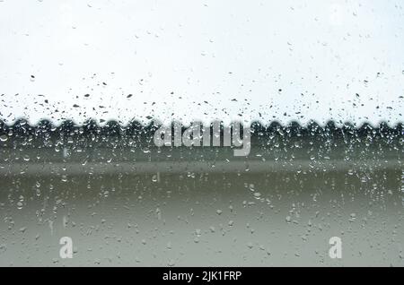 Regentropfen auf dem Fenster des Haushintergrunds Stockfoto