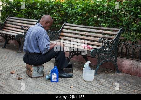 CARTAGENA DE INDIAS, KOLUMBIEN - AUGUST, 2011: Straßenschuhpolierer warten einsam auf Kunden im Bolivar Park in der ummauerten Stadt Cartagena Stockfoto