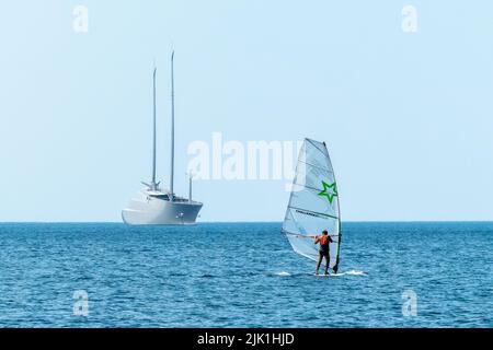 Triest, Italien, 28. Juli 2022. Ein Mann surft in der Nähe der größten Segelyacht der Welt, die im adriatischen Hafen von Triest liegt. Die 530 Milli Stockfoto