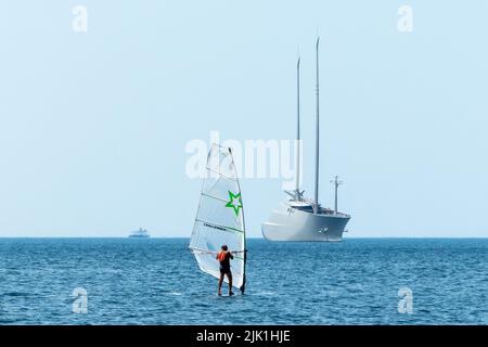 Triest, Italien, 28. Juli 2022. Ein Mann surft in der Nähe der größten Segelyacht der Welt, die im adriatischen Hafen von Triest liegt. Die 530 Milli Stockfoto