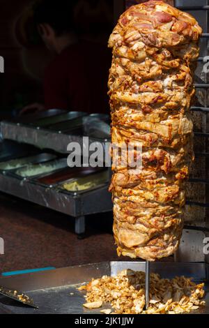 Nahaufnahme der gestapelten Fleischröstung, die für die Zubereitung von traditionellen griechischen Gyros oder türkischen Durum-Dönern verwendet werden kann. Kopierbereich mit verschwommenem Hintergrund Stockfoto