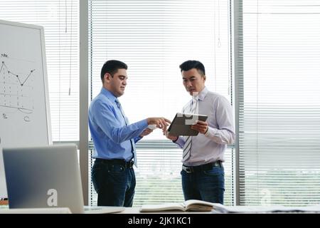 Geschäftsleute diskutieren etwas auf dem Bildschirm der digitalen Tablette Stockfoto
