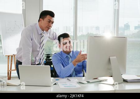 Geschäftsmann zeigt seine Arbeit einem vietnamesischen Kollegen Stockfoto