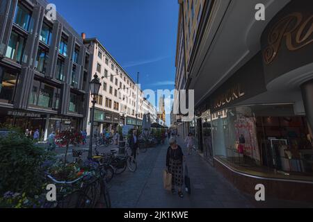 München, Deutschland - 6. Juli 2022: Stadtbild Straßenansicht Theatinerstrasse mit Blick auf die Theatinerkirche. Kirchturm oder Glockenturm mit seiner Uhr am e Stockfoto