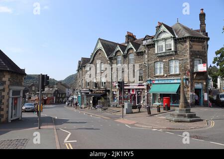 AMBLESIDE, ENGLAND, 18. JULI 2022: Blick auf das Ambleside Postamt und die Geschäfte im Stadtzentrum an der Rydal Road (A591) in Cumbria an einem sonnigen Sommertag. Amblesid Stockfoto