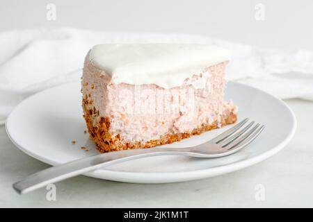 Scheibe Honey Lavender Cheesecake Nahaufnahme: Scheibe pastellfarbener Cheesecake auf einem Teller mit einer Gabel Stockfoto