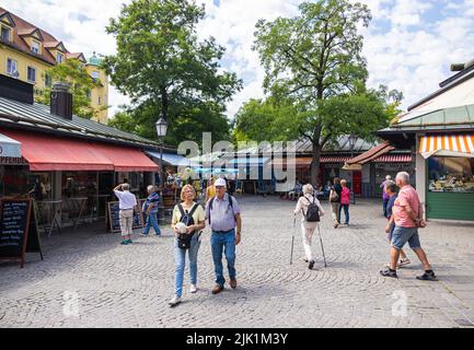 München, 6. Juli 2022: Blick über den Viktualienmarkt. Die Menschen schlendern durch den Platz, schauen und kaufen allerlei Dinge. Ein Blumenstand bei t Stockfoto