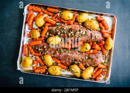 Marinierte Schweinefilets mit Gemüse auf einem Blech Pfanne: Roher Schweinebraten mit Babykartoffeln und Karotten auf einer Backform Stockfoto