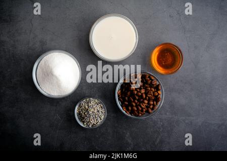 Honiglavender Cold Brew Latte Zutaten: Blick von oben auf Kaffeebohnen, gebratene Lavendelblüten und andere vereiste Latte-Zutaten Stockfoto