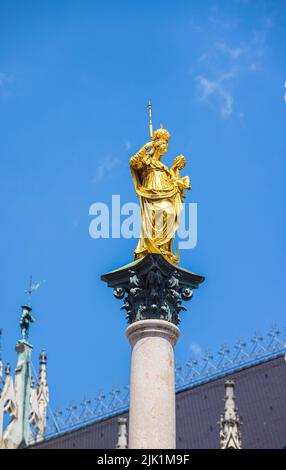 München, Deutschland - 6. Juli 2022: Die marianische Säule, gekrönt von einer vergoldeten Bronzestatue der Jungfrau Maria. Die goldene Statue oder Skulptur mit einem klaren BL Stockfoto