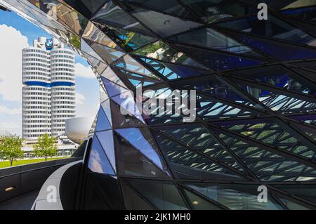 München, 6. Juli 2022: Blick an der Glasfassade der BMW World vorbei zum Hauptsitz der BMW AG und zum BMW Museum. Befindet sich neben dem Auto facto Stockfoto