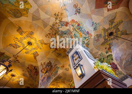 München, Deutschland - 6. Juli 2022: Im Hofbräuhaus mit detailreicher traditioneller Deckenmalerei. Blick nach oben an der Decke, vorbei an der Säule mit dem alten adv Stockfoto