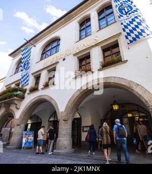 München, Deutschland - 6. Juli 2022: Die Königliche Brauerei in München, das Münchener Hofbräuhaus am Platzl. Ein muss für Touristen. Die bayerische Flagge und das HB-Logo Stockfoto