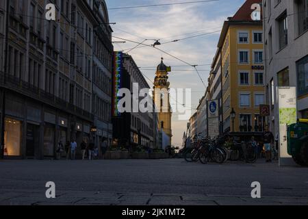 München, Deutschland - 6. Juli 2022: Blick auf die Theatinerstraße mit Blick auf die Theatinerkirche bei Sonnenuntergang. Der Kirchturm oder Glockenturm mit i Stockfoto
