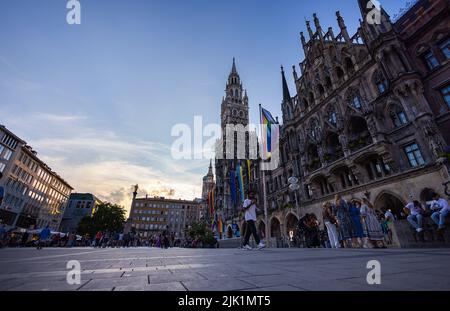 München, Deutschland - 6. Juli 2022: Sonnenuntergang am Marienplatz. Es ist der Hauptplatz der Stadt mit dem neuen Rathaus. In der Mitte o Stockfoto