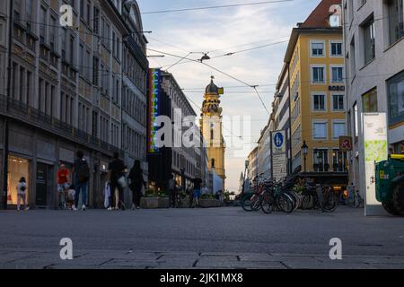 München, Deutschland - 6. Juli 2022: Blick auf die Theatinerstraße mit Blick auf die Theatinerkirche bei Sonnenuntergang. Der Kirchturm oder Glockenturm mit i Stockfoto