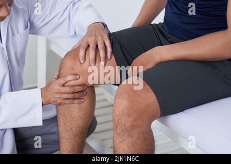 Nahaufnahme eines Arztes, der beim männlichen Patienten auf das Knie kniet Stockfoto