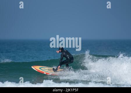 Spektakuläre Surfaktionen, während ein Surfer eine Welle im Fistral in Newquay in Cornwall im Vereinigten Königreich reitet. Stockfoto