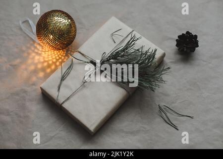 Weihnachtskomposition auf Bastelpapier-Hintergrund mit Geschenkbox, Tannenzweigen, Spielzeug, Kopierraum für Ihre Glückwünsche Stockfoto