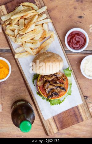 Gemüse-Cheeseburger mit Pilzen, Salat, Tomaten, Cheddar-Käse und Ei, mit pommes frites Stockfoto