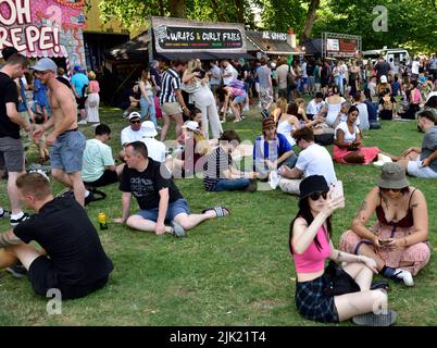 Massen von Menschen, die sich am heißen Sommertag auf dem Rasen im „Queens Square“ neben den Imbissständen entspannen, Bristol Harbour Festival, Großbritannien Stockfoto