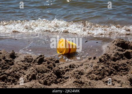 Verlassene gelbe Plastikkübel Sand Spielzeug an einem Strand Stockfoto