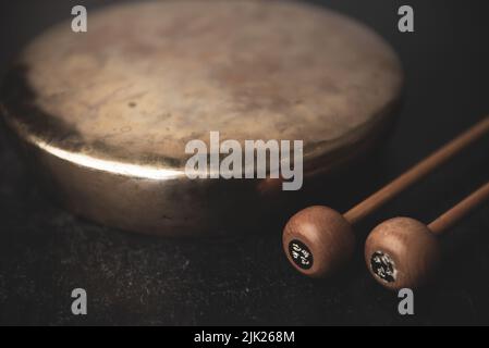 Jing Koreanischer traditioneller Gong mit Schlagstöcken auf dunklem launischem Hintergrund Stockfoto