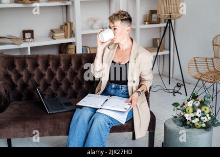 Eigenes Unternehmen Gründen. Junge trendige Frau plant neues Projekt mit Papieren und Laptop im Heimbüro Stockfoto