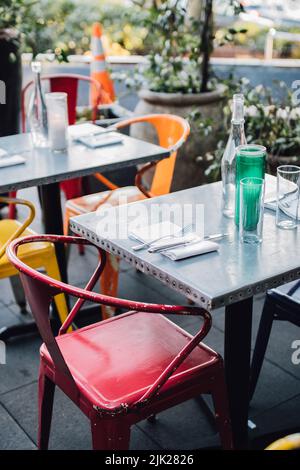 Tische im Freien mit farbigen Metallstühlen im Restaurant Stockfoto