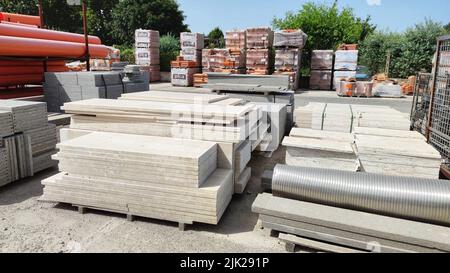 Paletten und Pakete aus frisch produzierten roten Ziegeln in einem Baulager auf der Straße. Konzept der Reparatur und Baustoffe Stockfoto