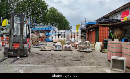 Paletten und Pakete aus frisch produzierten roten Ziegeln in einem Baulager auf der Straße. Konzept der Reparatur und Baustoffe Stockfoto