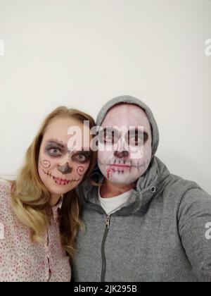 Junge Menschen mit einem bemalten Schädel auf ihrem Gesicht auf weißem Hintergrund. Feier des Tages der Toten Stockfoto