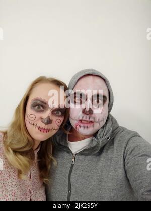 Junge Menschen mit einem bemalten Schädel auf ihrem Gesicht auf weißem Hintergrund. Feier des Tages der Toten Stockfoto