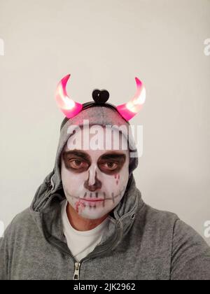 Ein junger Mann mit einem bemalten Schädel auf seinem Gesicht auf weißem Hintergrund. Feier des Tages der Toten Stockfoto