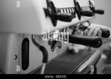 Der Barista hält einen Halter und macht Kaffee mit einer Doppelkessel-Kaffeemaschine Stockfoto