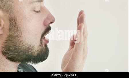 Schlechter Atem. Das Konzept der Mundgeruch. Ein junger Mann prüft seinen Atem mit der Hand Stockfoto