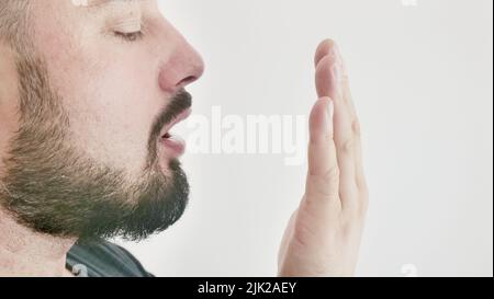 Schlechter Atem. Das Konzept der Mundgeruch. Ein junger Mann prüft seinen Atem mit der Hand Stockfoto