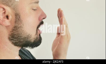 Schlechter Atem. Das Konzept der Mundgeruch. Ein junger Mann prüft seinen Atem mit der Hand Stockfoto