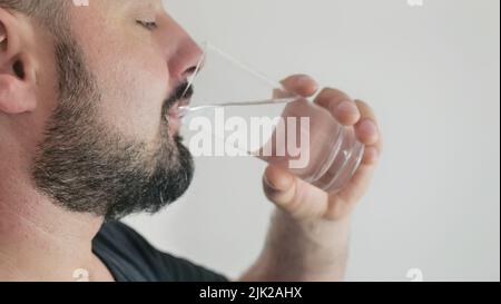 Ein junger Mann trinkt Wasser aus einem Glas Stockfoto