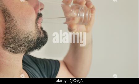 Ein junger Mann trinkt Wasser aus einem Glas Stockfoto