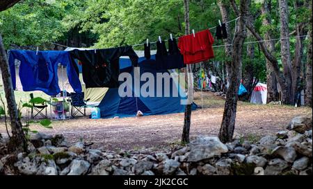 Teil des offenen Touristenzeltes Nahaufnahme Camping im Wald. Touristisches Leben - Kleidung wird getrocknet, Schuhe in der Nähe des Zeltes Stockfoto