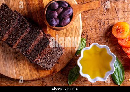 Natives Olivenöl extra, Tomaten, Basilikum, Oliven und Schwarzbrot. Stockfoto