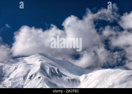 Wolken über verschneiten Bergen Stockfoto
