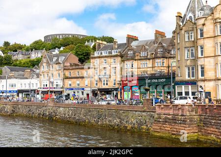 Oban Stadtzentrum an sonnigen Sommertagen, Geschäfte und Touristen in der Stadt mit Blick auf McCaig's Turm, Oban, Argyll, Schottland, Großbritannien Stockfoto