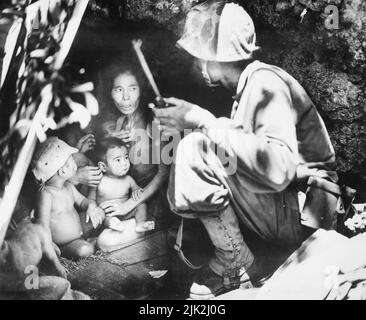 Ein Mitglied einer Marine Patrol auf Saipan fanden diese Familie von Jap versteckt sich in einem Hügel Höhle. Die Mutter, die vier Kinder und ein Hund, nahm Schutz von der heftigen Kämpfe in diesem Bereich. Stockfoto