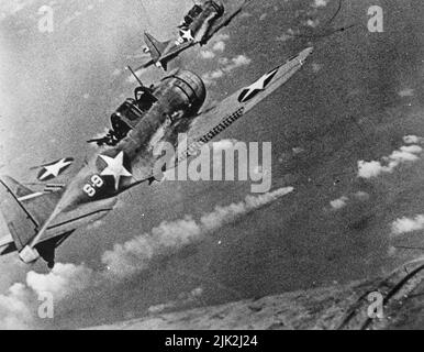 US Navy Douglas SBD-3 die untadeligen Tauchbomber der Scouting Squadron 8 (VS-8) des Flugzeugträgers USS Hornet (CV-8) nähern sich dem brennenden japanischen schweren Kreuzer Mikuma, um während der Schlacht von Midway am 6. Juni 1942 die dritte Angriffsgruppe auf sie zu machen. Stockfoto