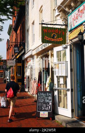 Eine junge Frau geht an Tavernen, Boutiquen und kleinen Unternehmen im Viertel Fells Point in Maryland vorbei Stockfoto