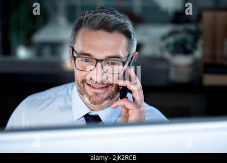 Ich schaute es mir gerade an. Ein Geschäftsmann sprach auf seinem Handy, während er an seinem Schreibtisch saß. Stockfoto