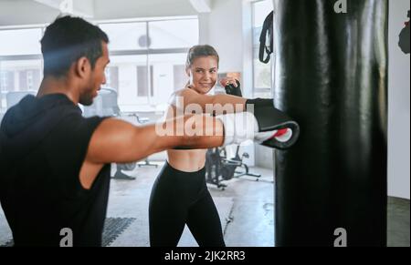 Aktiv und fit Mann und Frau Boxen, Training und Training gemeinsam für die Fitness im Fitnessstudio. Junges, sportliches und seriöses Paar, das eine Routine-Kardio macht Stockfoto