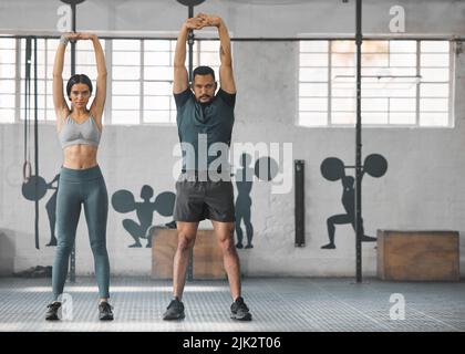 Fitness, aktives und gesundes Paar Stretching, Training oder Training zusammen im Fitnessstudio. Zwei junge Fitnesstrainer, die ein Ganzkörper-Workout machen oder Stockfoto